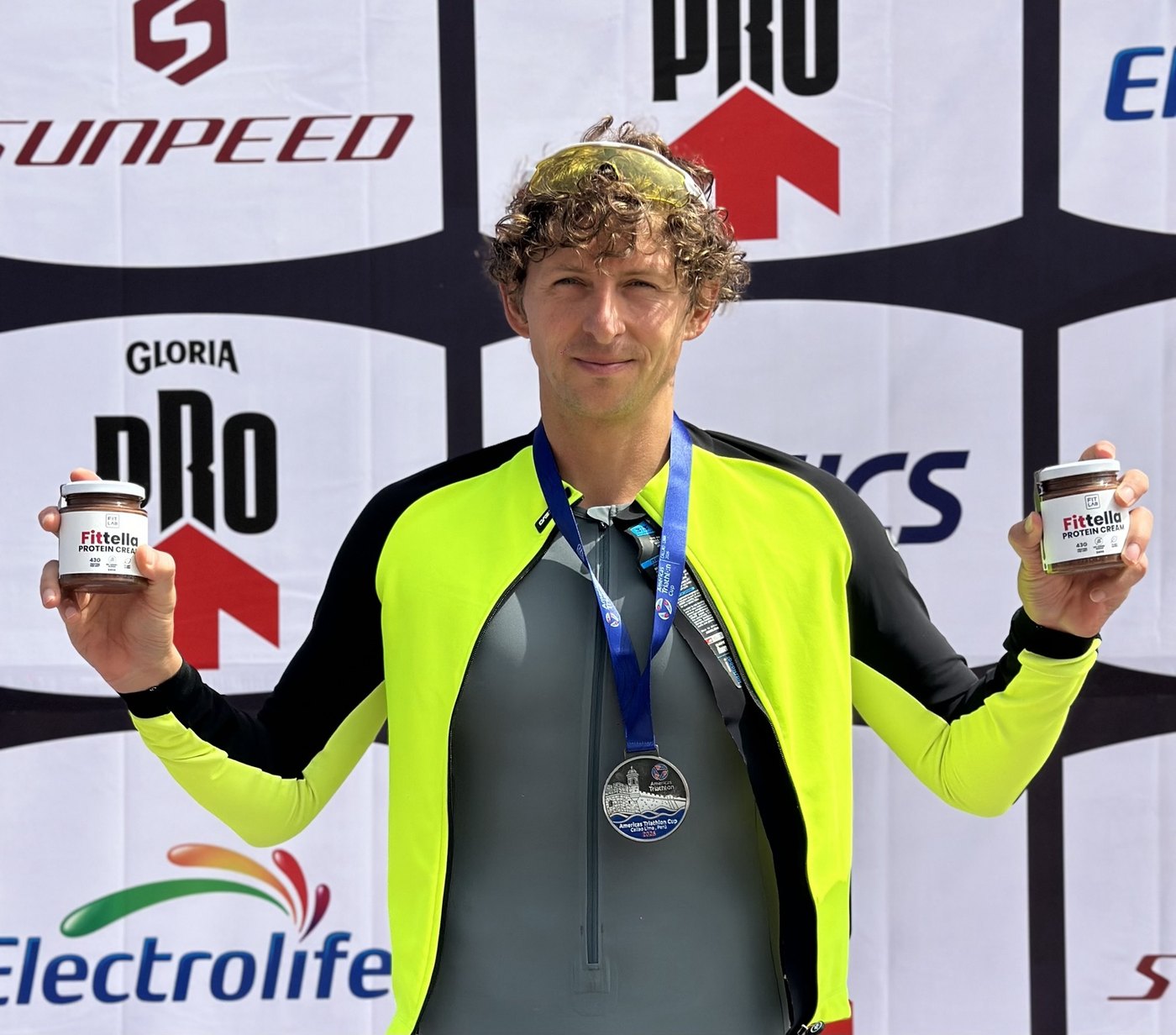 Atleta en el podio de la Americas Triathlon Cup sosteniendo dos frascos de Fittella